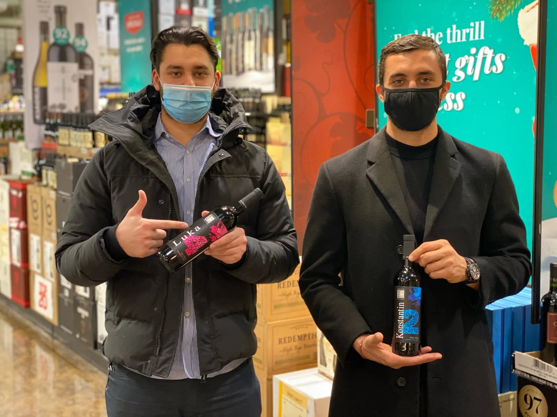 Two people in face masks holding bottles of Lanchava Collection wine, one of them Konstantin, inside a wine store